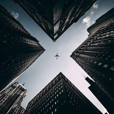 an airplane is flying through the sky between tall buildings