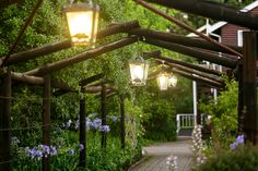 an outdoor walkway is lit up with two lanterns and flowers on either side of the path