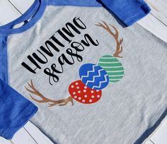 a shirt that says hunting and eggs with antlers on the front, sitting on top of a wooden table