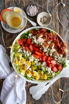 a salad with chicken, lettuce and tomatoes in a white bowl on a wooden table