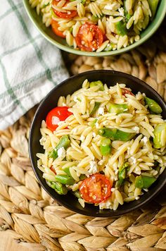 two bowls filled with pasta and vegetables on top of a table