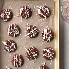 chocolate covered cookies with white icing and sprinkles on a baking sheet