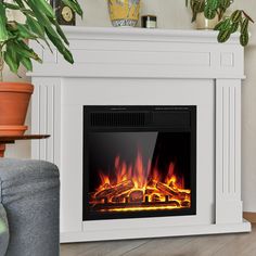 a white fireplace with bright flames in the center and potted plants on either side