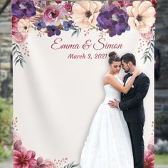 a bride and groom hugging each other in front of a floral wedding photo banner with the words,'emma & simon'on it