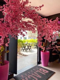 pink flowers are in large vases at the entrance to an eater's restaurant