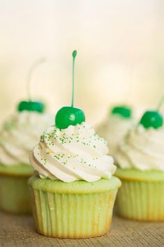 cupcakes with white frosting and green sprinkles on top are lined up