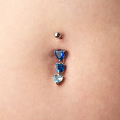 a woman's belly with two blue heart shaped jewels attached to the side of her stomach