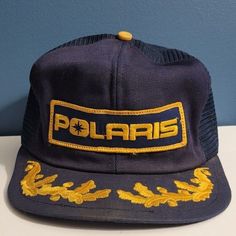 POLARIS vintage hat  Navy and gold mesh trucker cap, snapback Patch says "Polaris" with scrambled eggs on the bill Made in USA by K-Products FAIR vintage condition.  See photos for condition, and please don't hesitate to message me with any questions. Brim is broken (has folds) in several spots (see last photo), and stitching is coming out in two areas.  Patch is in excellent condition!  Some dirt spots on mesh. Vintage Navy Snapback Hat With Flat Bill, Vintage Navy Snapback Hat, Vintage Winter Trucker Snapback Hat, Vintage Winter Snapback Trucker Hat, Vintage Snapback Hat With Embroidered Patch, Vintage Gold Cap Hat, Vintage Adjustable Trucker Hat With Embroidered Patch, Casual Gold Trucker Hat With Curved Brim, Gold Trucker Hat For Streetwear