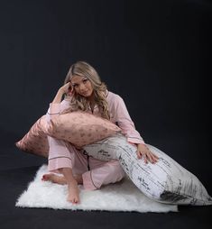 a woman sitting on top of a white fluffy rug holding a pillow and talking on a cell phone