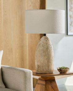 a table lamp sitting on top of a wooden table next to a white couch and chair