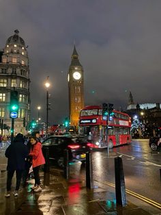 two people standing on the sidewalk near a busy street with traffic and big ben in the background