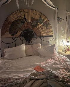 a bed with white sheets, pillows and a fan on the headboard above it