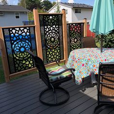 an outdoor table and chairs on a deck with umbrellas over it, next to a fence