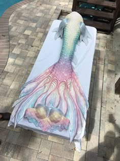 an image of a mermaid tail on a beach towel next to a swimming pool with sand in it