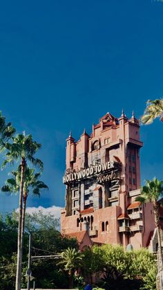 the hollywood tower hotel is pink and has palm trees in front of it on a sunny day