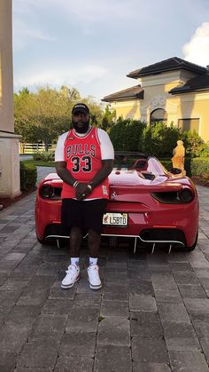 a man sitting on top of a red sports car