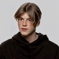 a young man in a black hoodie looking at the camera