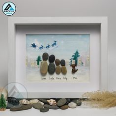 a white frame with some rocks on top of it and a painting in the middle