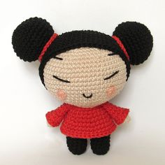 a crocheted doll with black ears and red dress