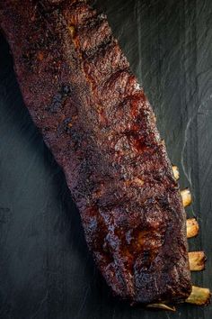 a large piece of meat sitting on top of a black table next to some fries