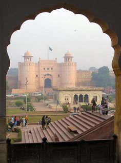 an archway leading to a palace with people riding horses