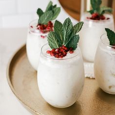 three glasses filled with yogurt and garnished with mint leaves on a plate