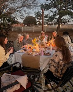 a group of women sitting around a table eating food