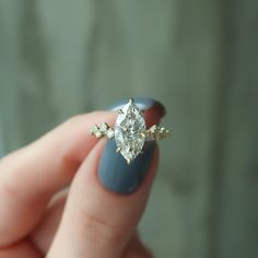 a woman's hand holding a ring with a diamond on it and two diamonds in the middle