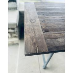 a wooden table with metal legs sitting outside