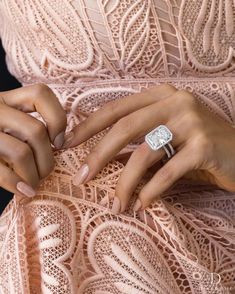 a woman in a pink dress holding onto her engagement ring