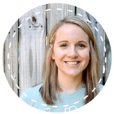 a woman with long hair and blue shirt smiling in front of a wooden fence background