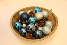 a wooden bowl filled with christmas ornaments on top of a table