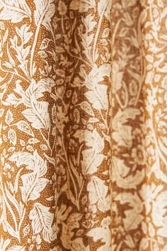 closeup of an orange and white curtain with brown floral designs on it's side