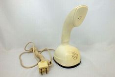 an old style telephone is sitting on the ground next to a corded phone plugged in