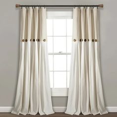 a white curtain hanging on the side of a window in front of a wooden floor