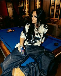 a woman sitting on top of a pool table next to a blue billiarde