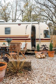 an rv is parked in the gravel next to some potted plants