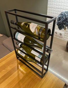 there is a wine rack with several bottles in it on the counter next to a vase