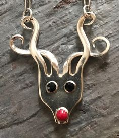 a silver necklace with a red nose and black eyes