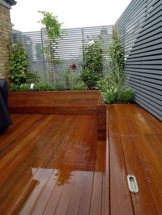 a wooden deck with planters and benches on the top floor, next to a brick wall