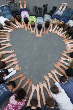 a group of children standing in a circle with their hands together to form the shape of a heart