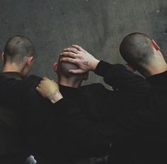 three men with their hands on each other's shoulders looking at something in the distance