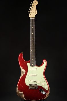 a red and white guitar sitting on top of a wooden stand