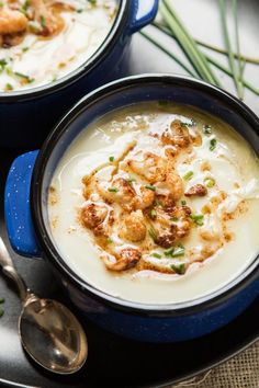 two blue bowls filled with soup and garnished with scallops on top