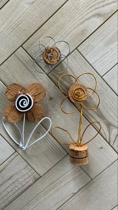 three metal flowers sitting on top of a wooden floor next to each other with wire wrapped around them