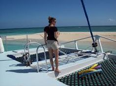 a woman standing on the deck of a boat looking out at the ocean and beach