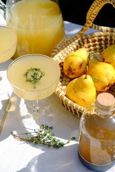 a table topped with two glasses filled with lemonade next to bottles and bowls full of lemonade