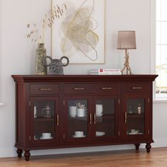 a large wooden cabinet with glass doors in a living room next to a painting on the wall