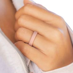 a woman's hand with a pink ring on her left wrist, wearing a white sweater