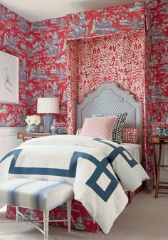 a bedroom with red and blue wallpaper, white bedding and an upholstered headboard